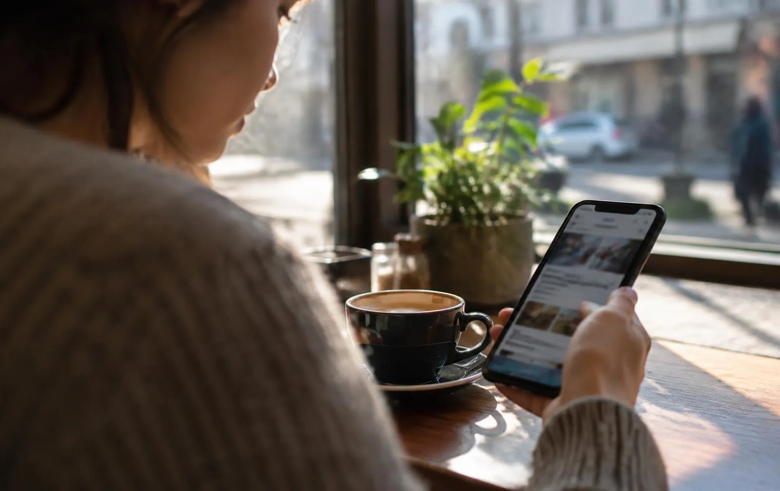 A person using a phone app in a sunlit cafe